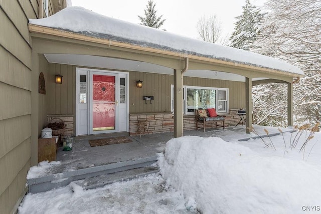 snow covered property entrance featuring stone siding