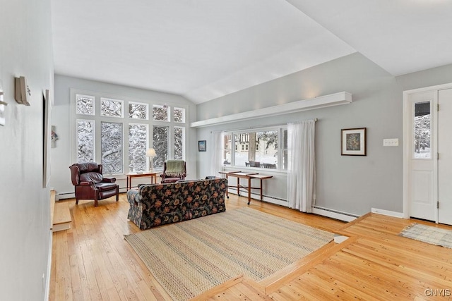 living room featuring light wood-style floors, lofted ceiling, and a baseboard heating unit