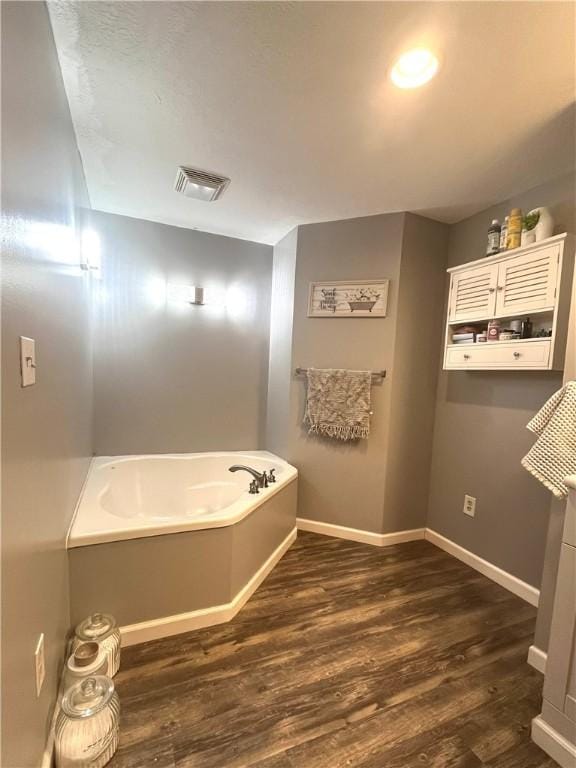 full bathroom with a garden tub, wood finished floors, visible vents, and baseboards