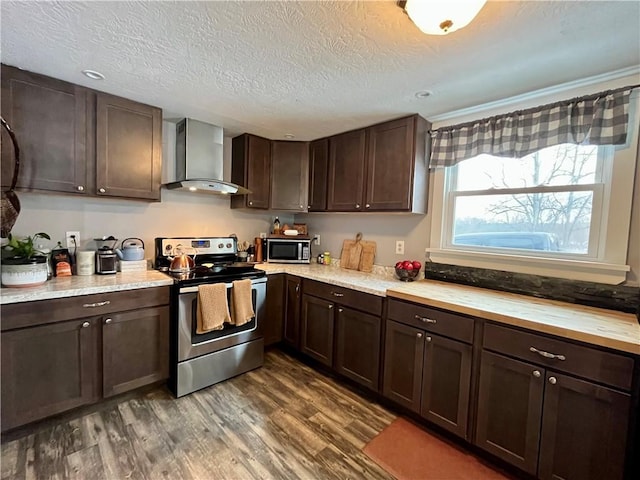 kitchen featuring dark brown cabinetry, wall chimney exhaust hood, stainless steel appliances, and dark wood finished floors