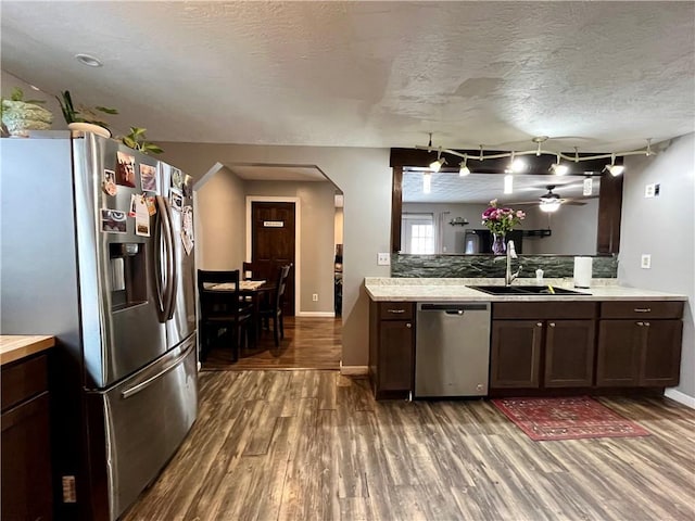 kitchen featuring appliances with stainless steel finishes, light countertops, a sink, and dark brown cabinetry