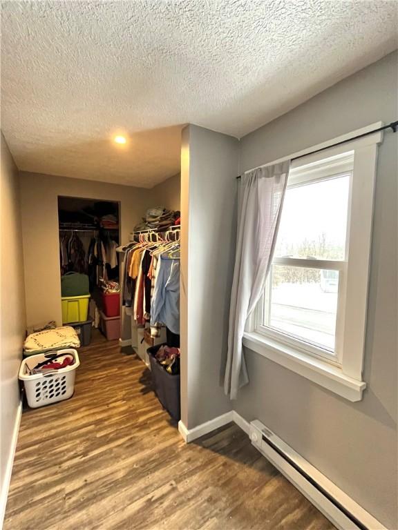 walk in closet featuring a baseboard radiator and wood finished floors