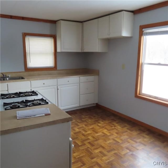 kitchen featuring light countertops, cooktop, a sink, and white cabinets