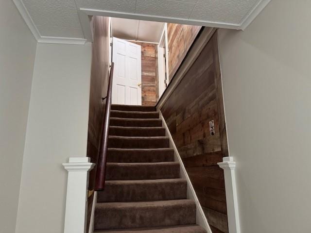 staircase with ornamental molding and a textured ceiling