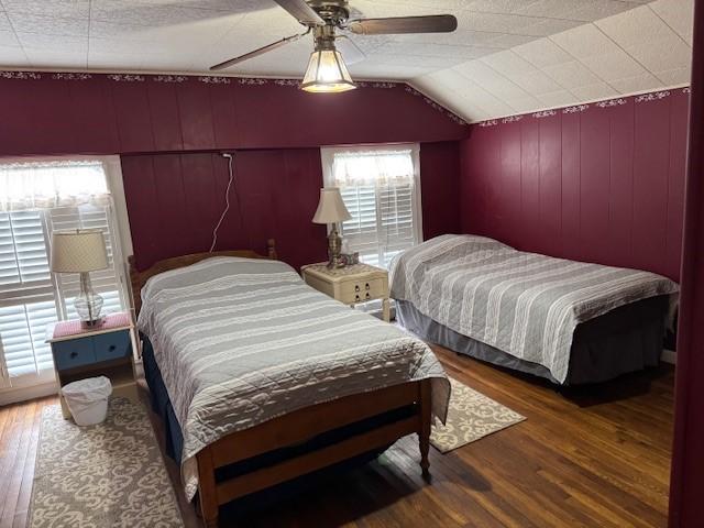 bedroom with a ceiling fan, lofted ceiling, and wood finished floors