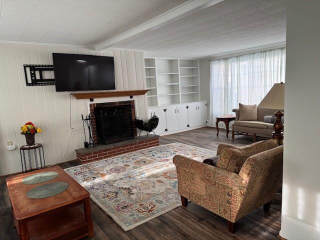 living room featuring built in features, a brick fireplace, and wood finished floors