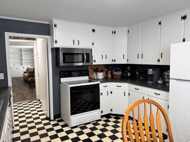 kitchen featuring range with electric cooktop, stainless steel microwave, dark countertops, freestanding refrigerator, and light floors