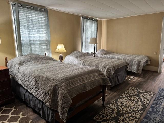 bedroom with ornamental molding, baseboards, and dark wood-style flooring