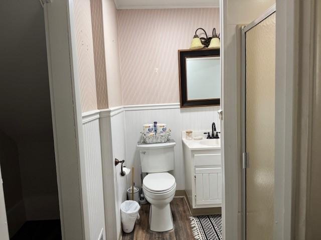 bathroom with toilet, a stall shower, wood finished floors, wainscoting, and vanity