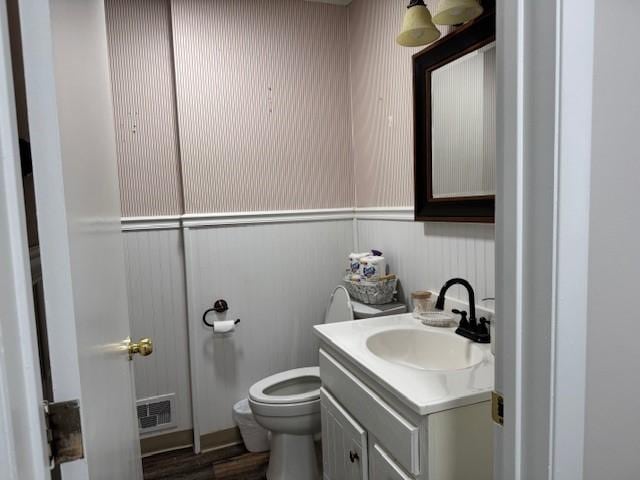 half bathroom with vanity, toilet, and visible vents