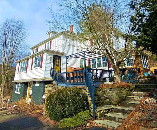 traditional style home with a chimney, a deck, and a pergola