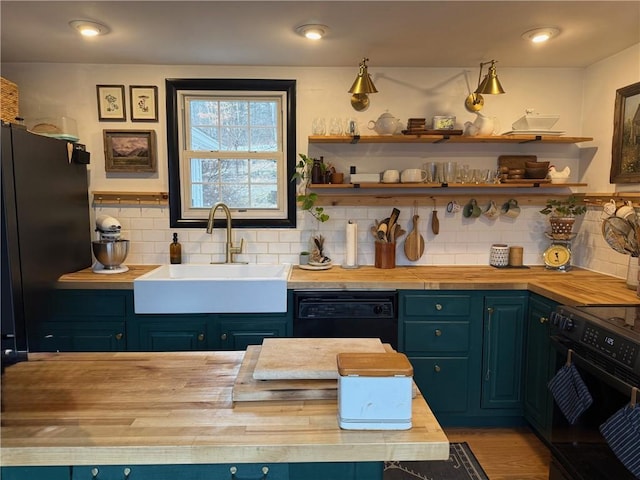 kitchen featuring open shelves, a sink, wood counters, blue cabinetry, and black appliances