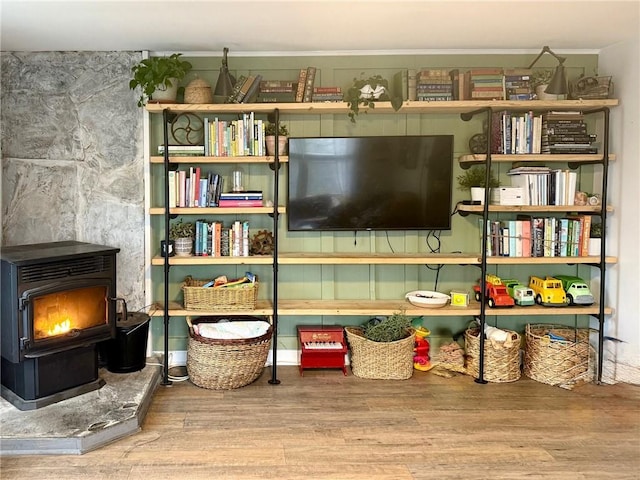 living area with a wood stove and wood finished floors