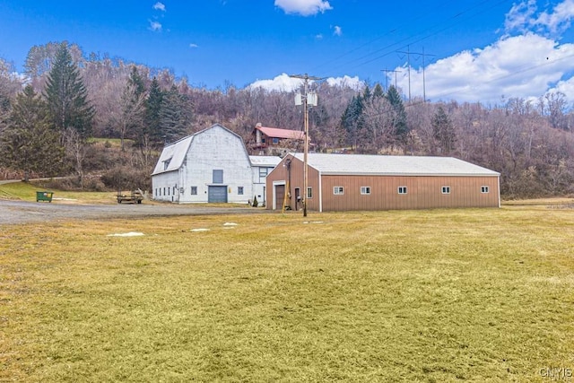 3391 State Route 28, Herkimer, NY 13350 - exterior space featuring a detached garage, a gambrel roof, a front lawn, an outdoor structure, and a forest view