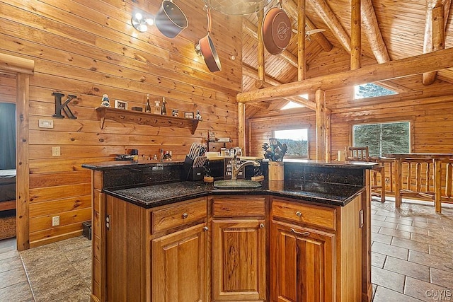 3391 State Route 28, Herkimer, NY 13350 - kitchen featuring an island with sink, wooden walls, brown cabinetry, and beam ceiling