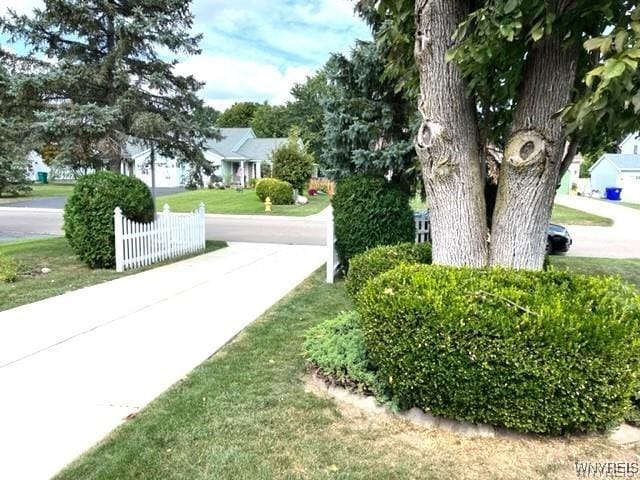 view of property's community featuring a residential view, fence, and a lawn