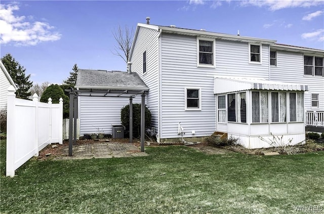 rear view of property with entry steps, a sunroom, fence, and a yard