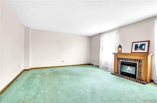 unfurnished living room featuring carpet floors, a fireplace, baseboards, and a textured ceiling