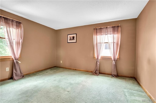 unfurnished room with light carpet, a textured ceiling, and baseboards