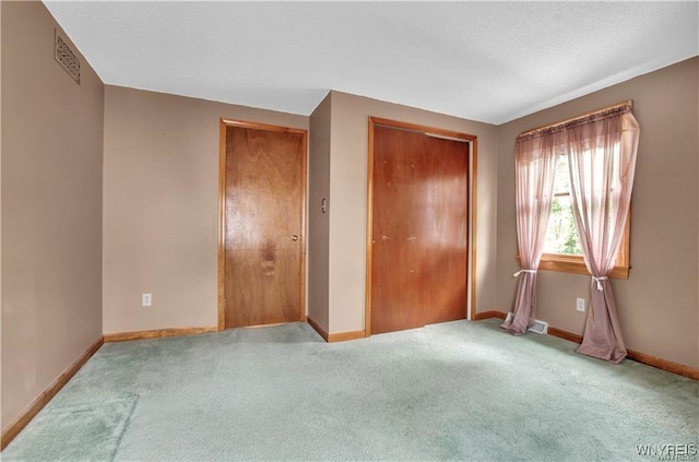 unfurnished bedroom featuring baseboards, visible vents, and light colored carpet