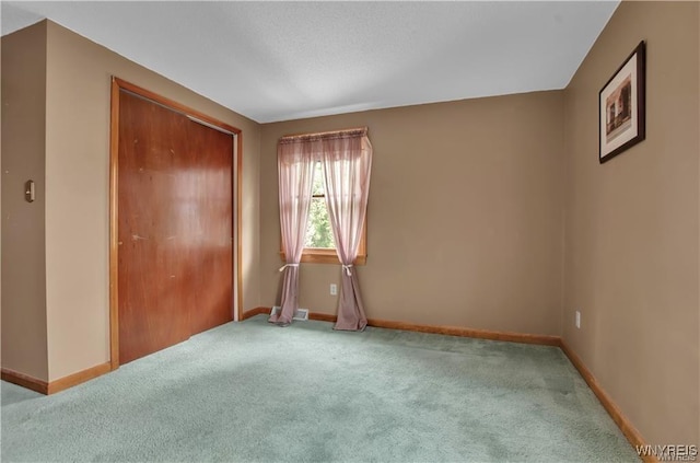 unfurnished bedroom with a closet, light colored carpet, and baseboards