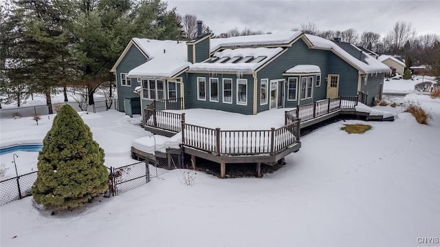 snow covered house featuring fence and a deck