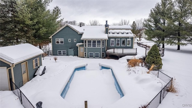 snow covered property with an outdoor pool, a wooden deck, and fence