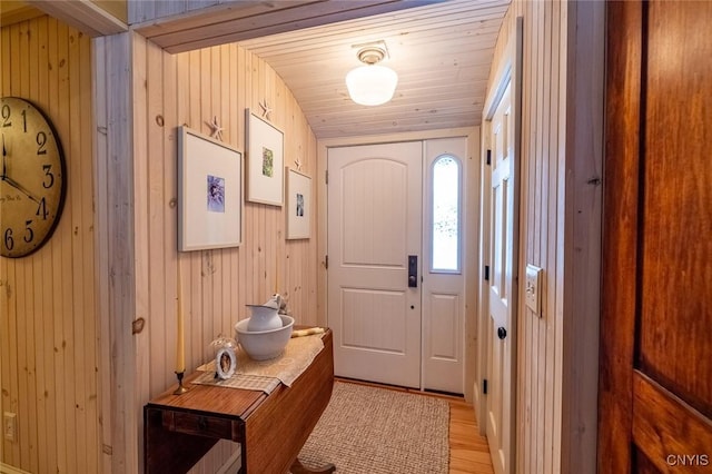 doorway with wood ceiling, wooden walls, and light wood finished floors