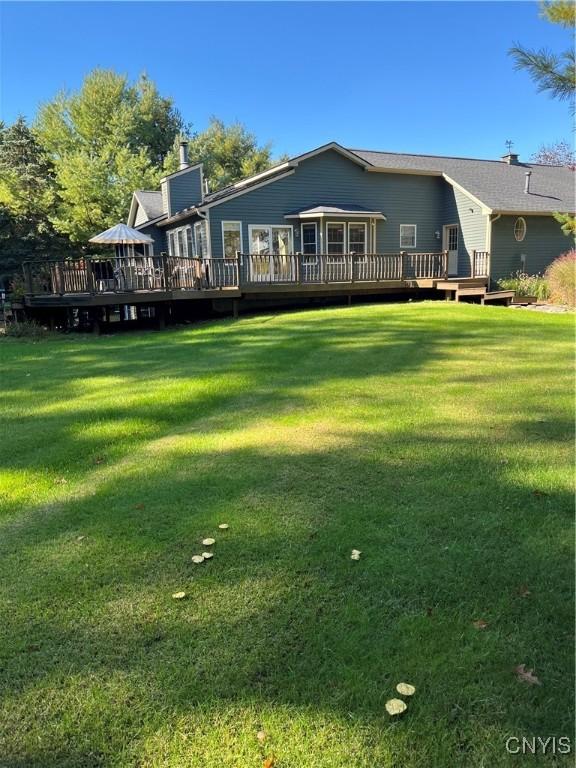 back of property featuring a yard and a wooden deck