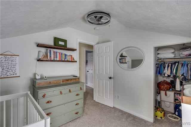 bedroom with vaulted ceiling, a textured ceiling, light carpet, and a closet