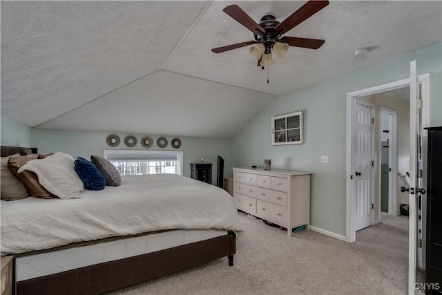 bedroom with ceiling fan, a textured ceiling, light colored carpet, baseboards, and vaulted ceiling