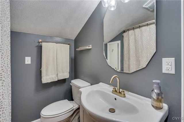 bathroom with a textured ceiling, a sink, toilet, and lofted ceiling