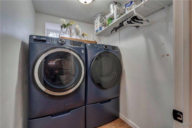 clothes washing area featuring washing machine and dryer, laundry area, and baseboards