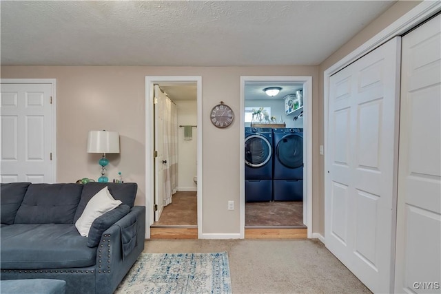 carpeted living area with baseboards, a textured ceiling, and washing machine and clothes dryer