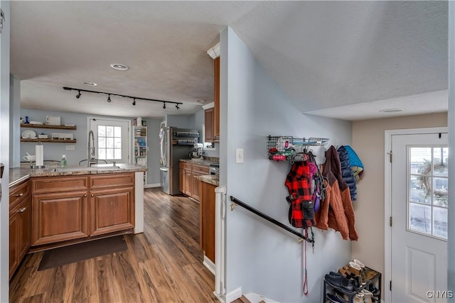 kitchen with a peninsula, brown cabinetry, wood finished floors, and freestanding refrigerator