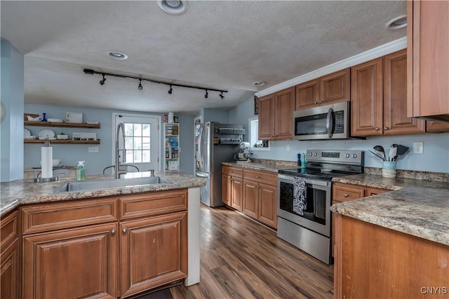 kitchen featuring a textured ceiling, dark wood-style flooring, a sink, appliances with stainless steel finishes, and brown cabinetry