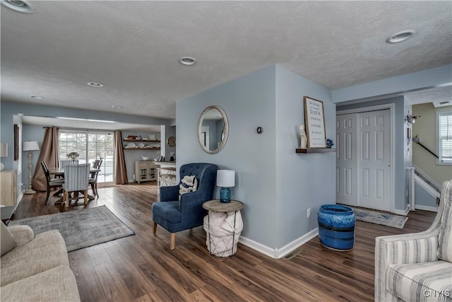 living room featuring plenty of natural light, a textured ceiling, baseboards, and wood finished floors