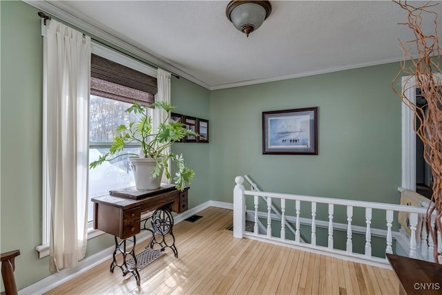 sitting room featuring ornamental molding, an upstairs landing, baseboards, and wood finished floors