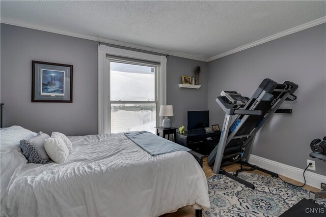 bedroom featuring crown molding, a textured ceiling, baseboards, and wood finished floors