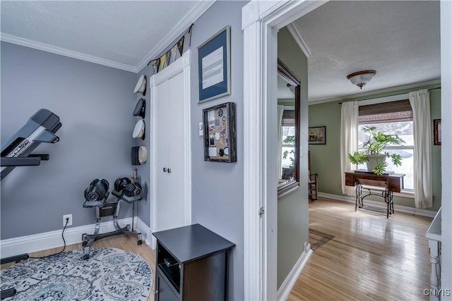 hall featuring light wood-style floors, baseboards, and ornamental molding