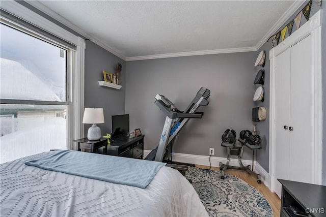 bedroom with ornamental molding, a closet, light wood-style flooring, and baseboards