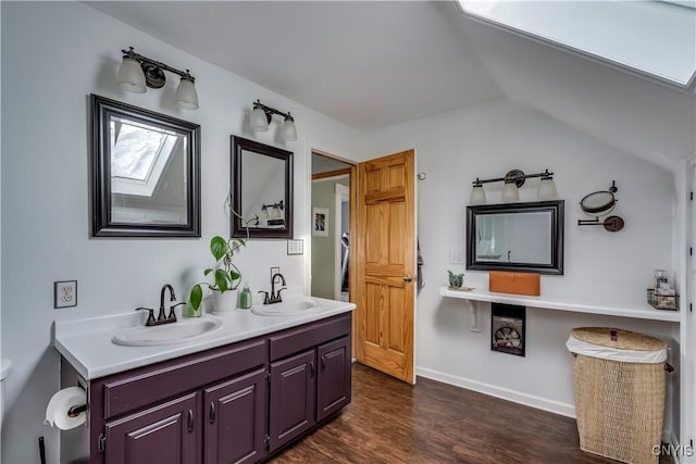 bathroom featuring a sink, vaulted ceiling with skylight, double vanity, and wood finished floors