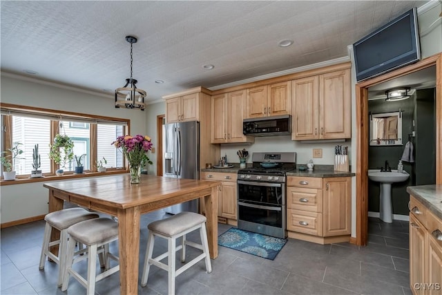 kitchen featuring dark countertops, stainless steel appliances, crown molding, and light brown cabinetry