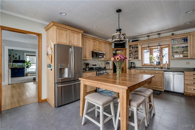 kitchen with light brown cabinets, decorative light fixtures, ornamental molding, appliances with stainless steel finishes, and glass insert cabinets