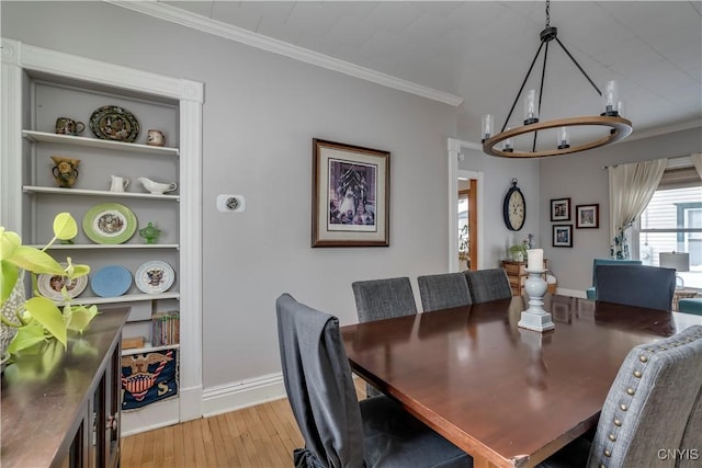 dining area with ornamental molding, built in shelves, light wood-style flooring, and baseboards