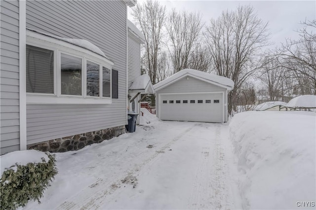 view of snow covered exterior featuring an outbuilding and a detached garage