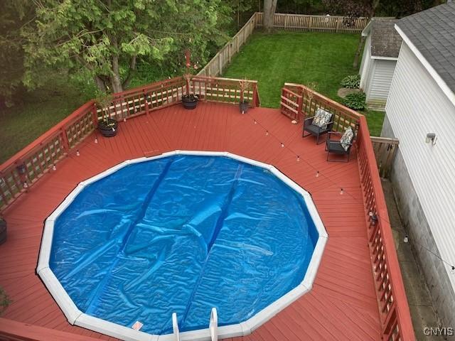 view of pool featuring a yard, a fenced backyard, and a deck