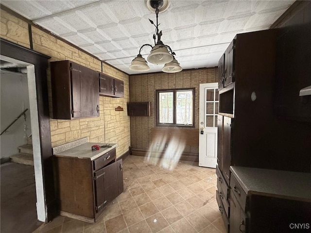 kitchen featuring an ornate ceiling, pendant lighting, and dark brown cabinetry