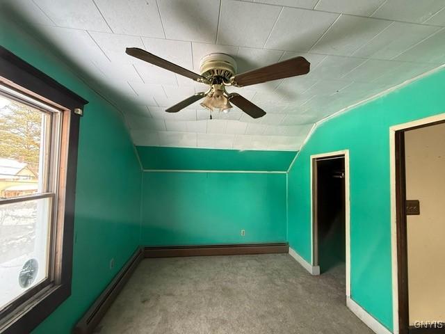 additional living space featuring light carpet, a baseboard radiator, baseboards, and vaulted ceiling