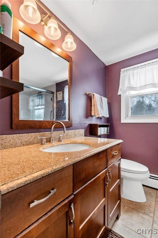 full bath with toilet, a stall shower, vanity, and tile patterned floors